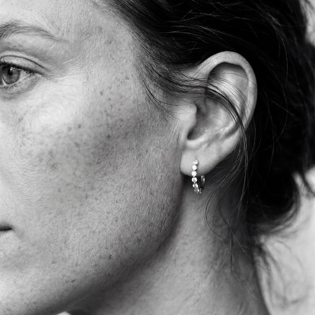 Close-up of a person wearing a small earring with a blurred background