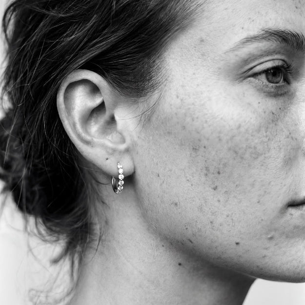 Close-up of a person wearing a small hoop earring with visible jewelry.