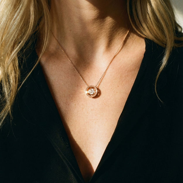 Close-up of a necklace with a pendant on a person wearing a black top.