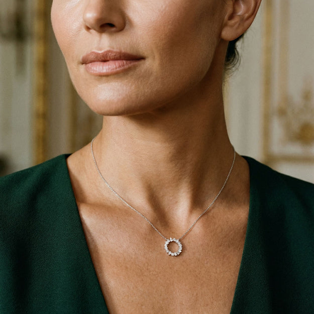 Woman wearing a delicate necklace with a circular pendant in an elegant indoor setting.