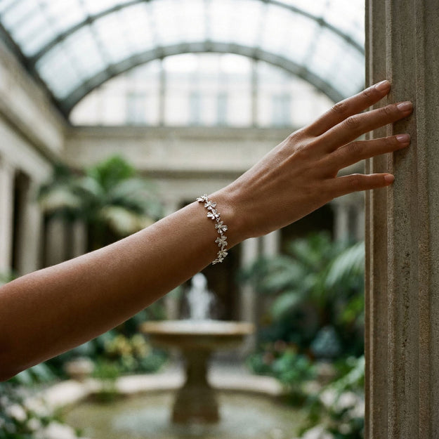 Hand wearing a bracelet with a blurred indoor garden background