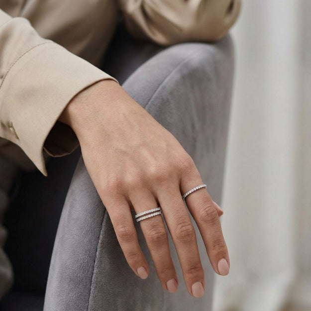 Close-up of a hand wearing two silver rings with a blurred background