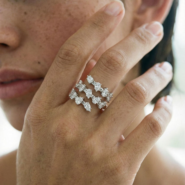 Close-up of a hand wearing two diamond rings with a blurred background