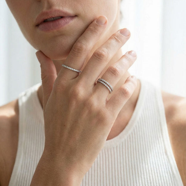 Close-up of a person wearing two silver rings on a blurred background