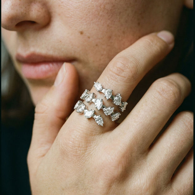 Close-up of a hand wearing multiple diamond rings on a blurred background