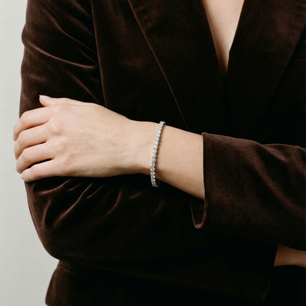 Person wearing a brown velvet outfit with a bracelet on a plain background