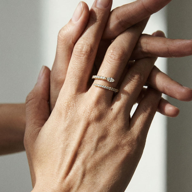 Close-up of two hands with diamond rings on a neutral background